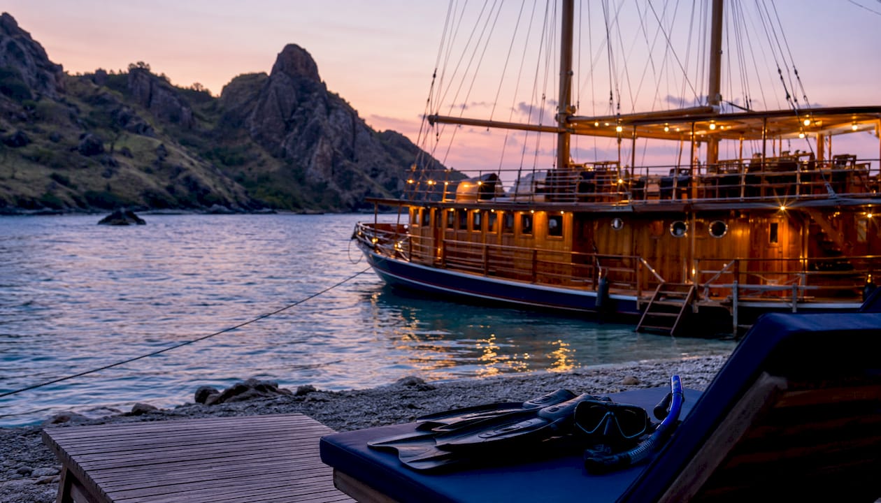 Luxury Phinisi yacht docked in Komodo at sunset