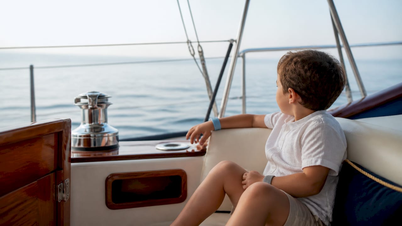 Child sitting in yacht cockpit wearing Sea-Bands