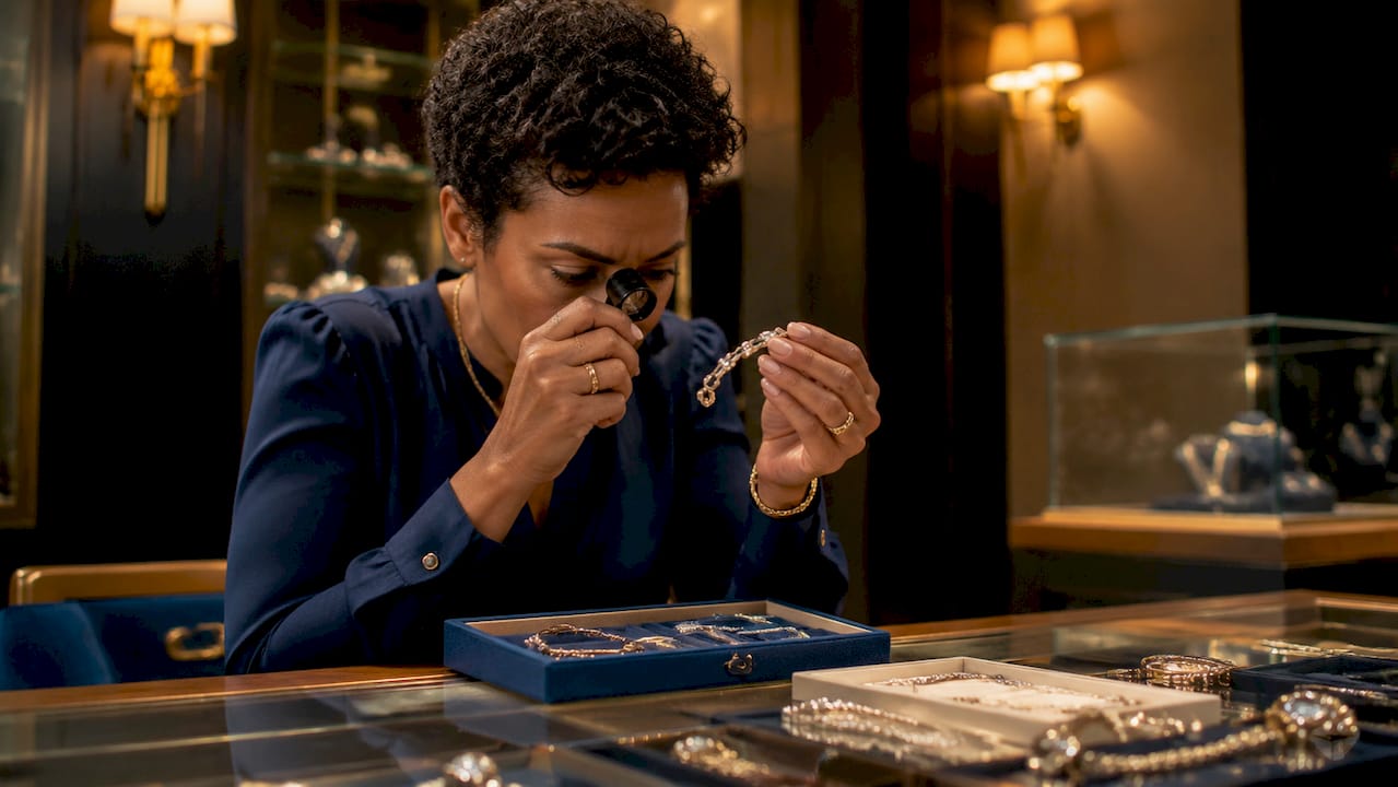 Jeweller examining costume bracelet with magnifier