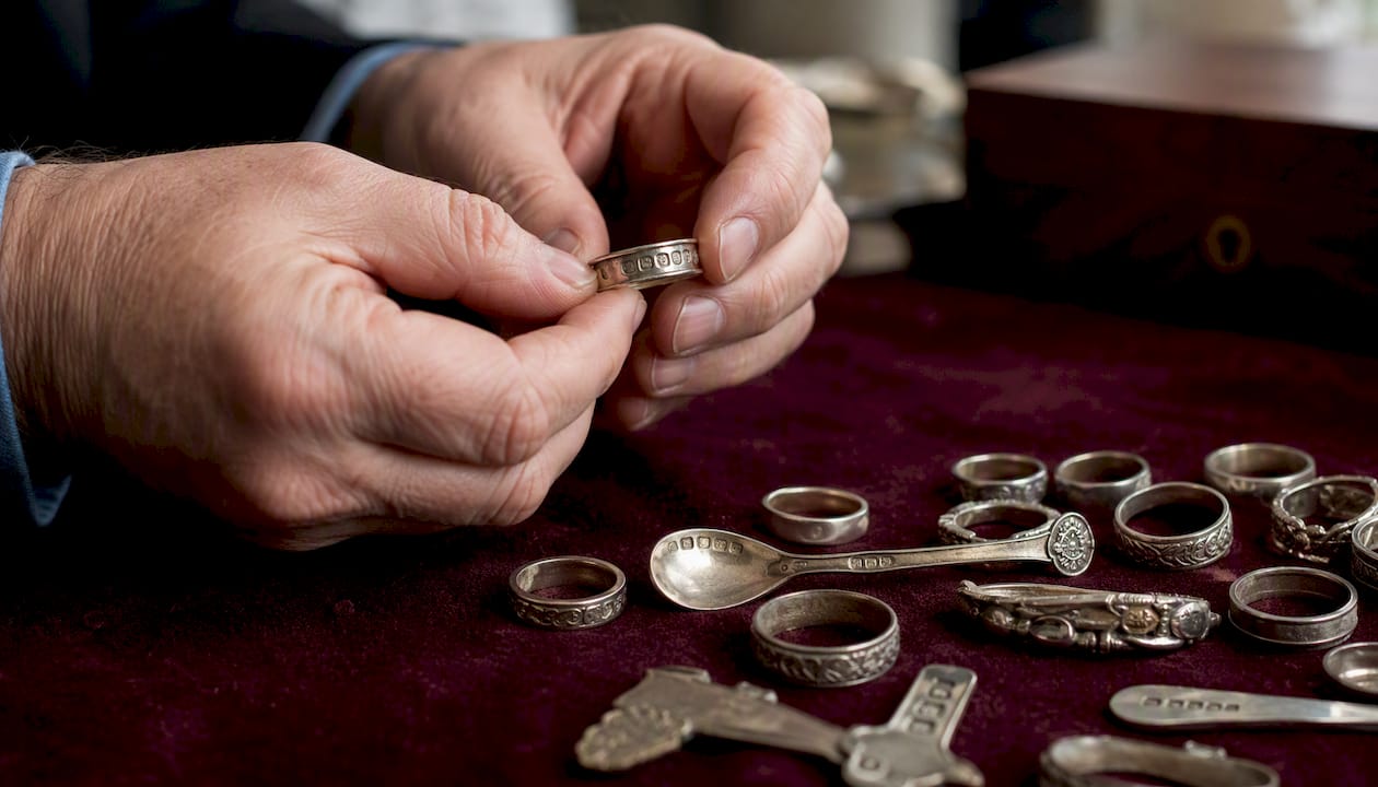 Hands inspecting second-hand silver jewellery hallmarks