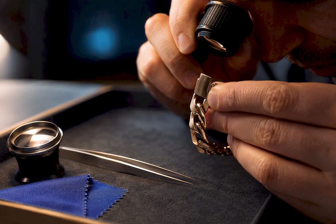 Jeweller inspecting bracelet clasp and hallmark