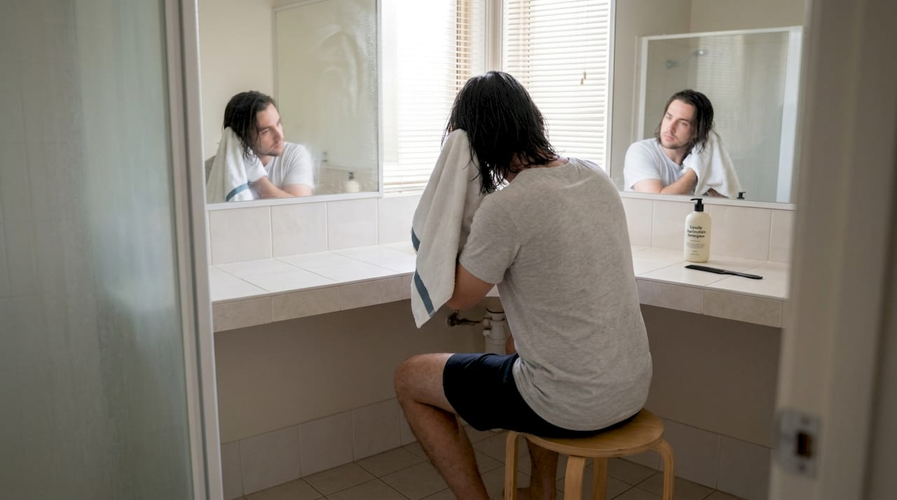 Man towel-drying hair with water on floor