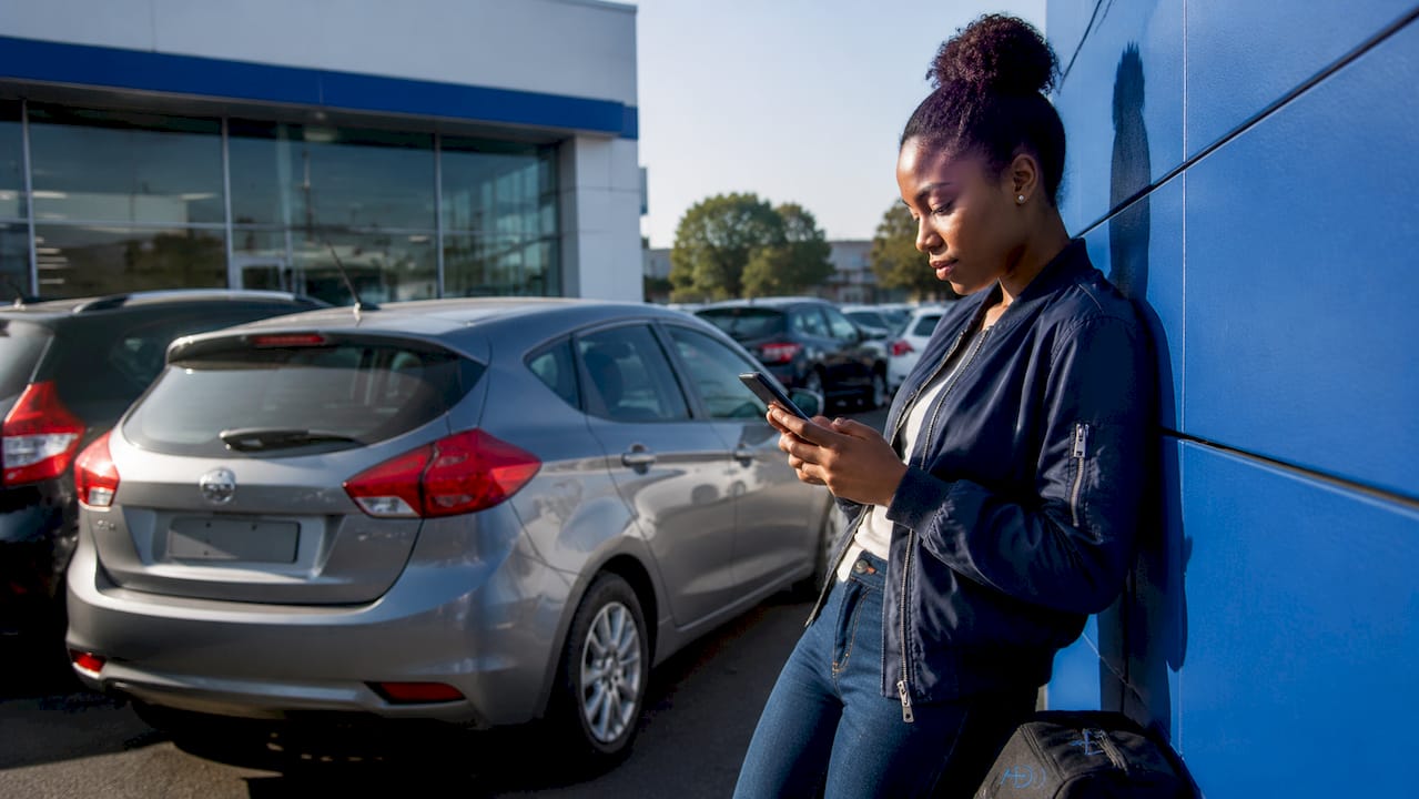 Woman checking car insurance on phone outdoors
