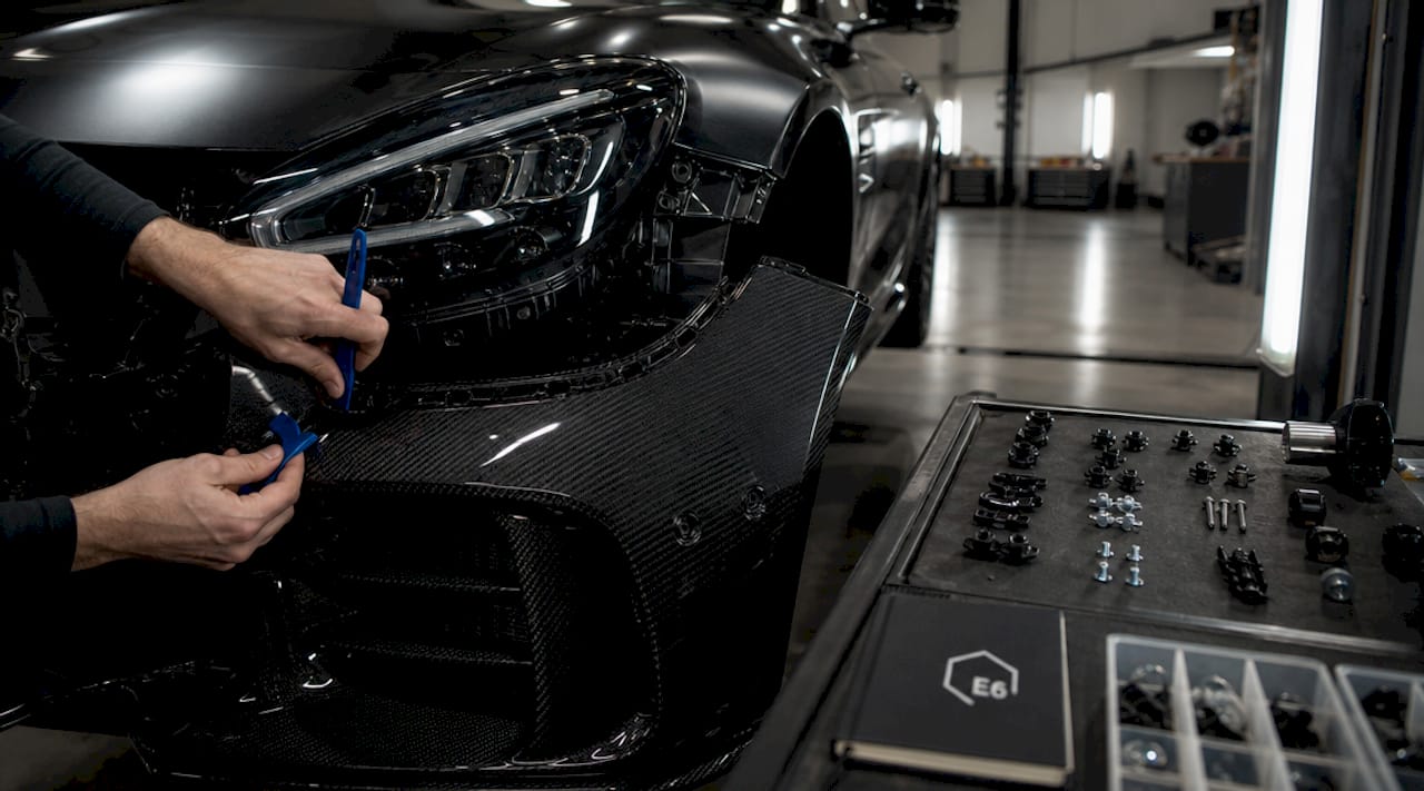 Close-up hands using trim removal tools on AMG bumper