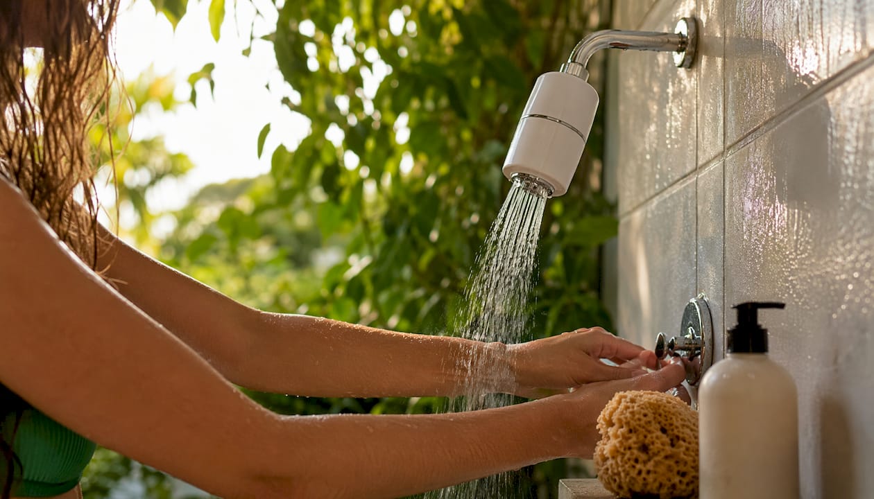 Hands adjusting shower with Vitamin C filter