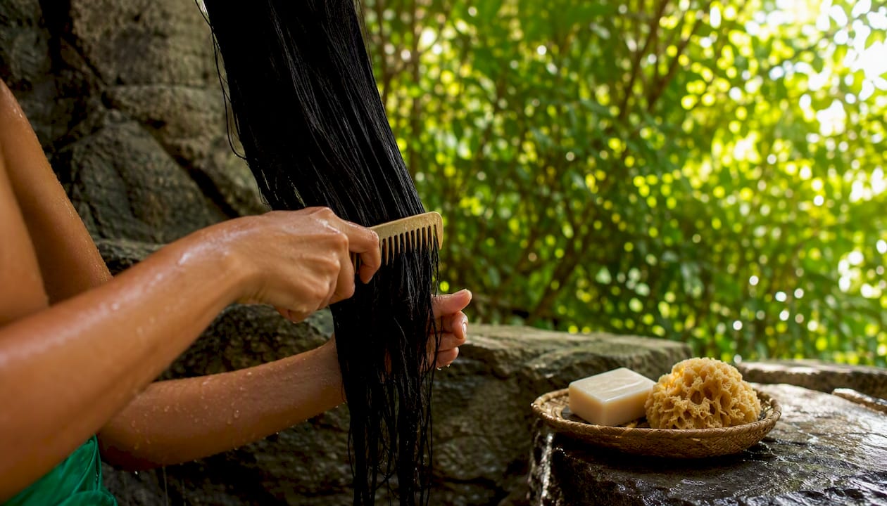 Hands detangling damp hair with wide-tooth comb