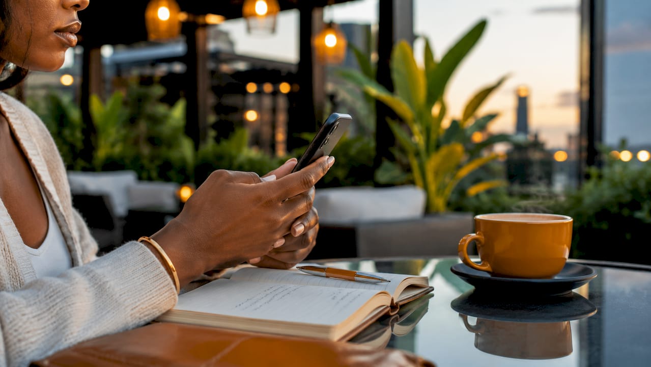 Hands using chauffeur booking app in café setting
