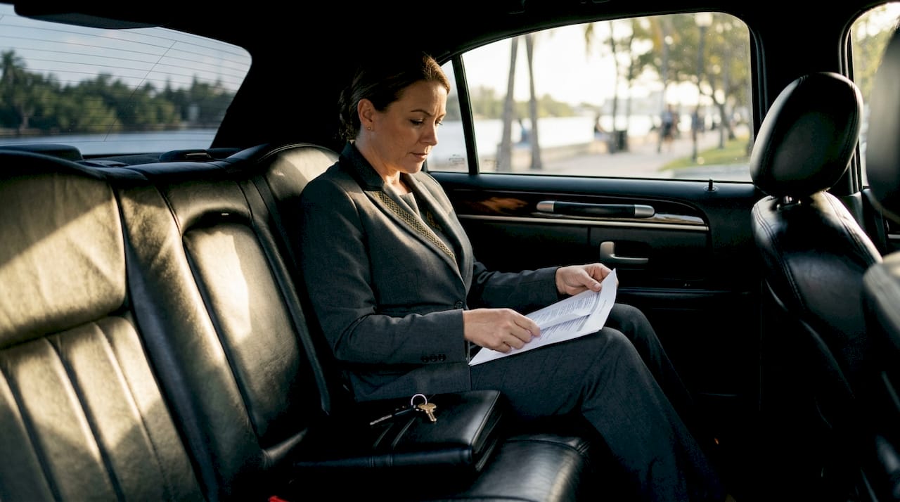 Chauffeur reviewing itinerary on tablet inside car