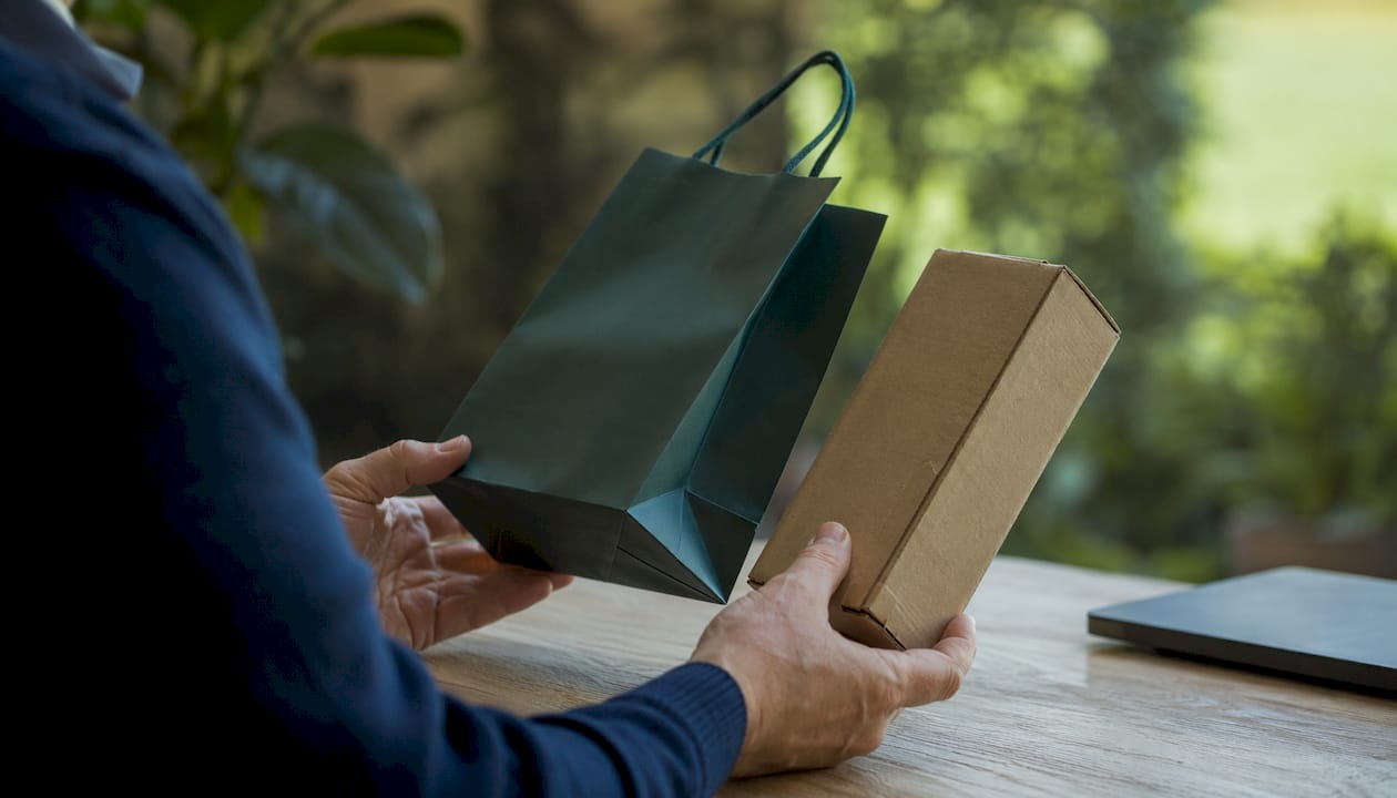 Hands comparing retail-ready and bulk paper bag packaging