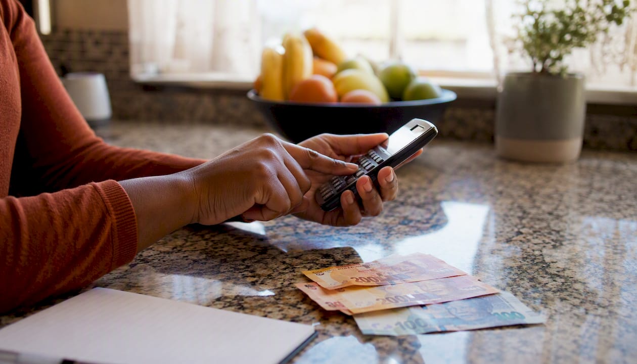 Hands calculating currency costs with calculator and naira