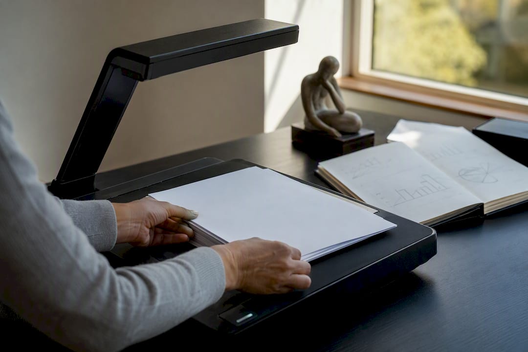 Hands loading sheets into document feeder
