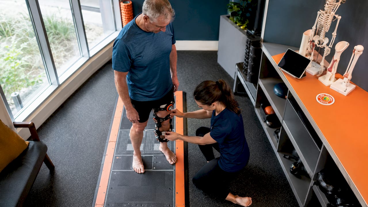 Physiotherapist adjusting APOS device on patient during clinical assessment