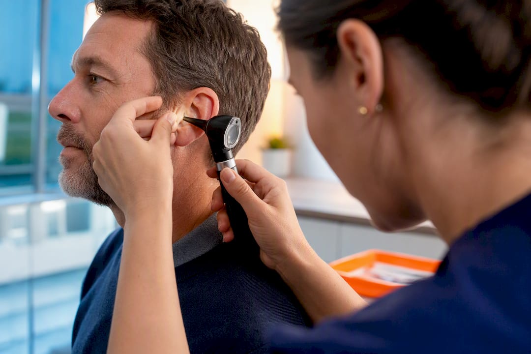 Clinician examining ear with an otoscope
