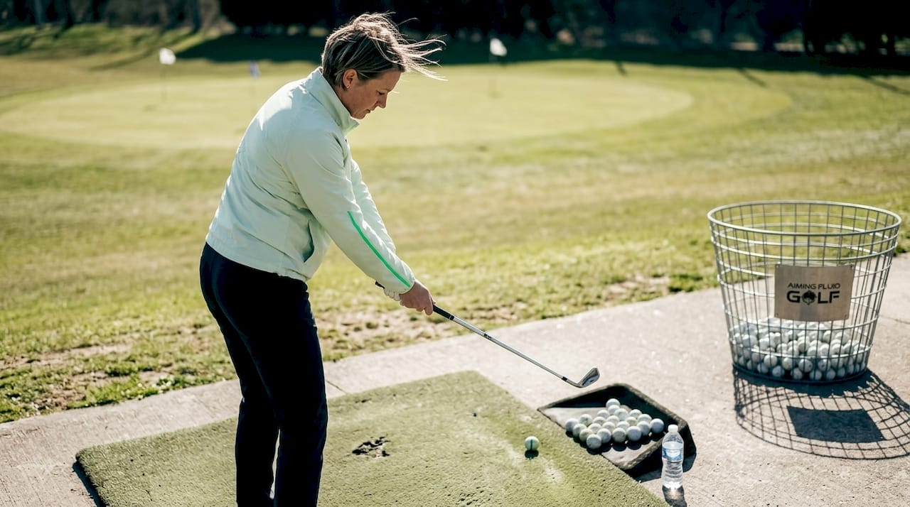 Woman practicing golf swing at driving range