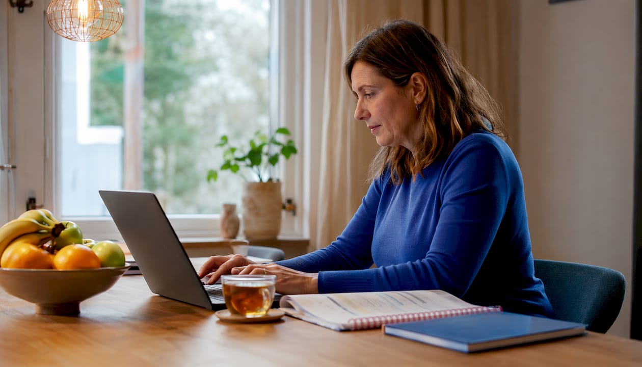 Een vrouw volgt een online training op haar werkplek.