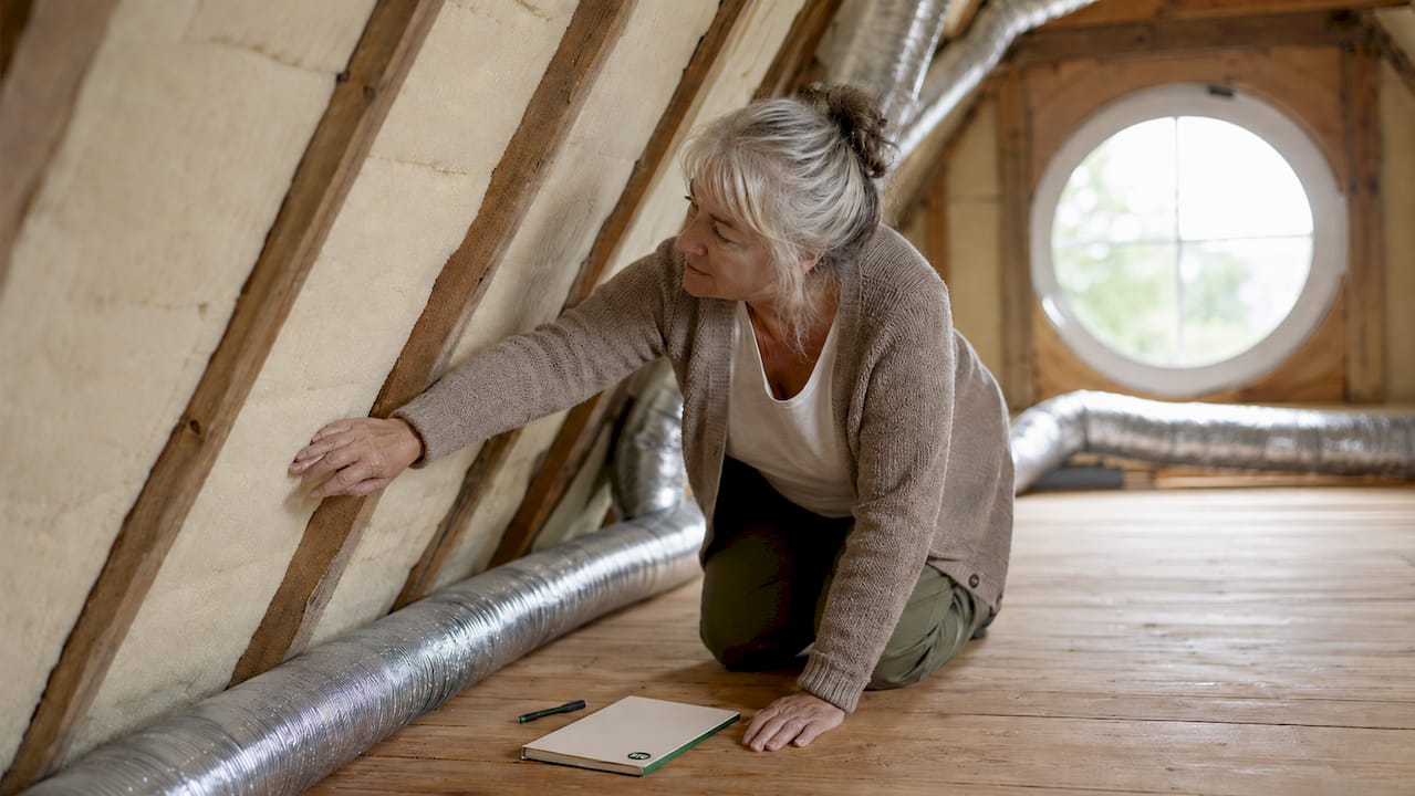 Woman inspecting attic insulation panels