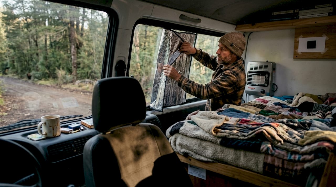 Viajero colocando aislamiento en su furgoneta camper durante la noche