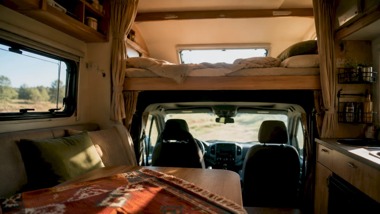 Zona interior de autocaravana capuchina con cama fija
