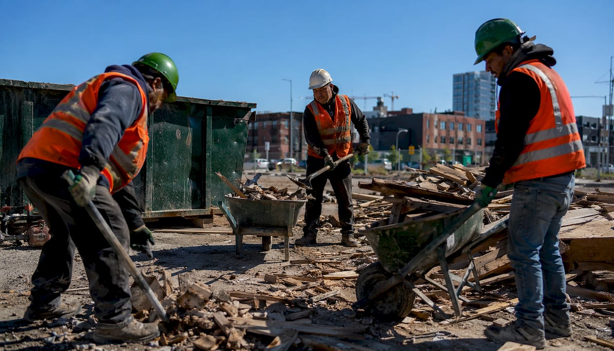 Workers removing construction debris with tools outdoors