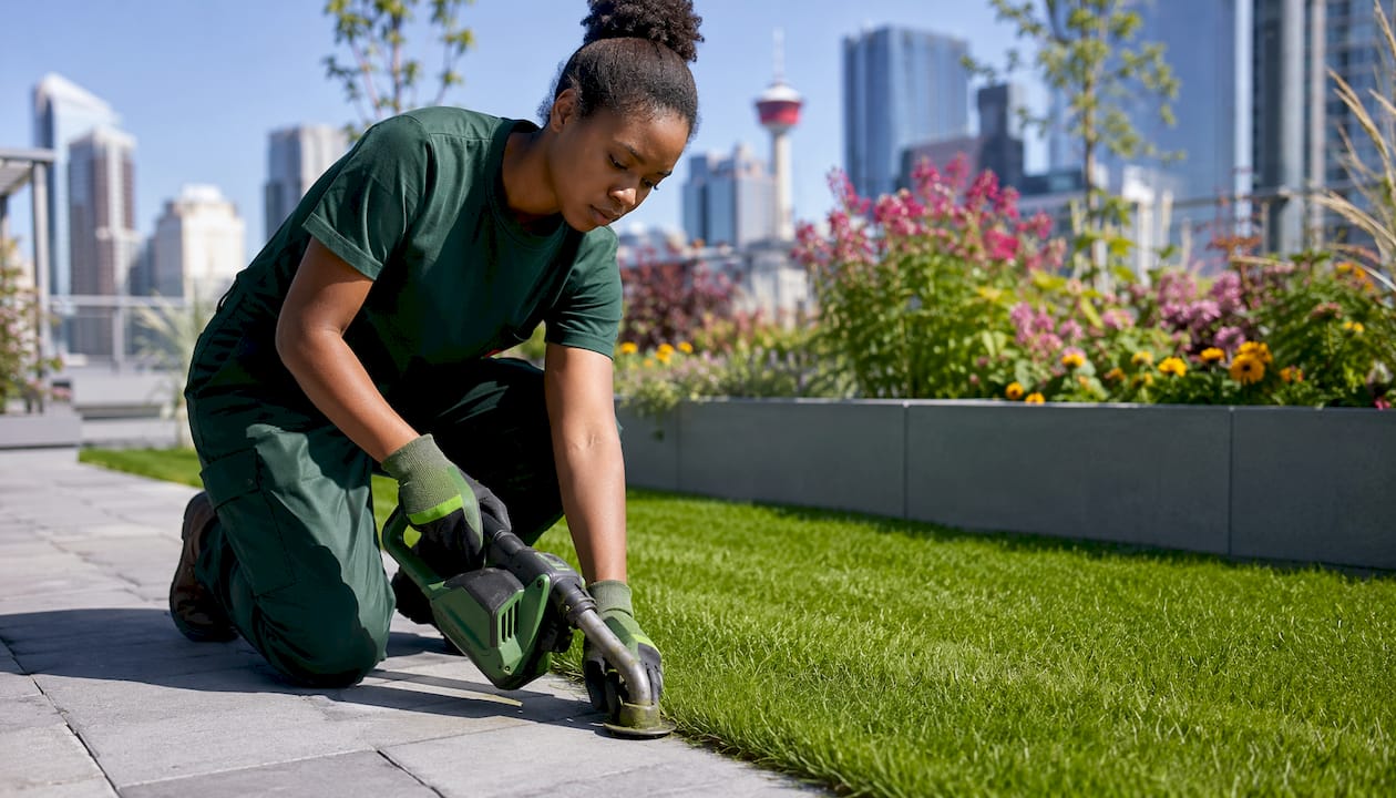 Technician trimming grass edges on walkway