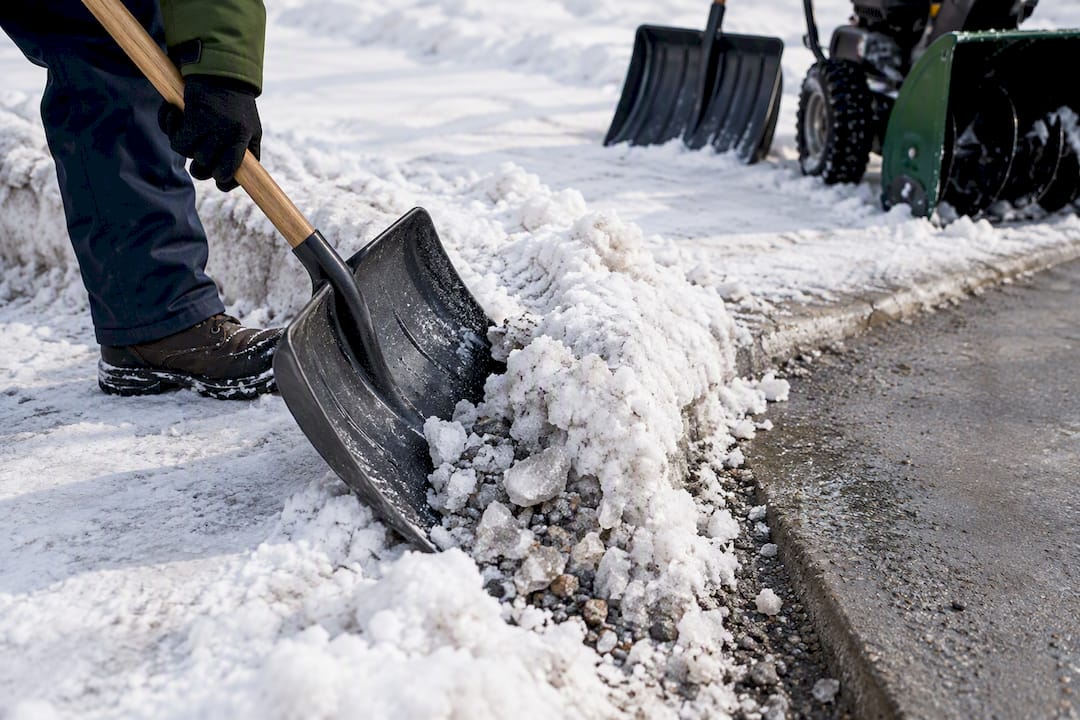 Shovel breaking a packed snow windrow