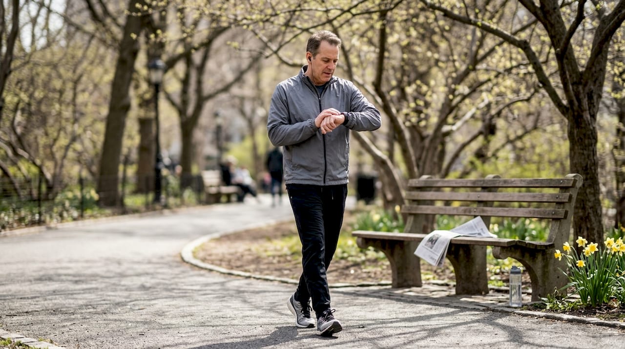 Man brisk walking on sunny park path
