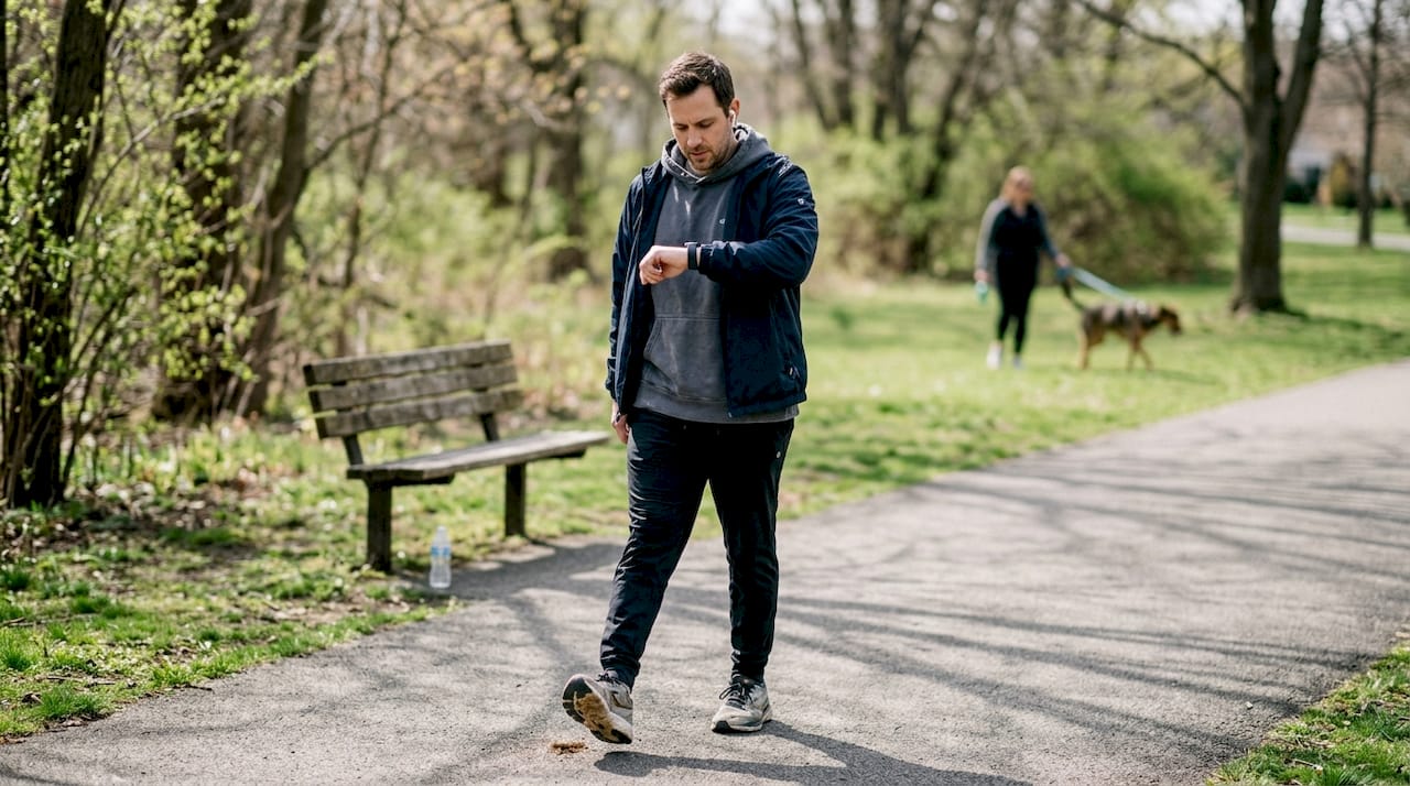 Man walking in park while tracking fitness