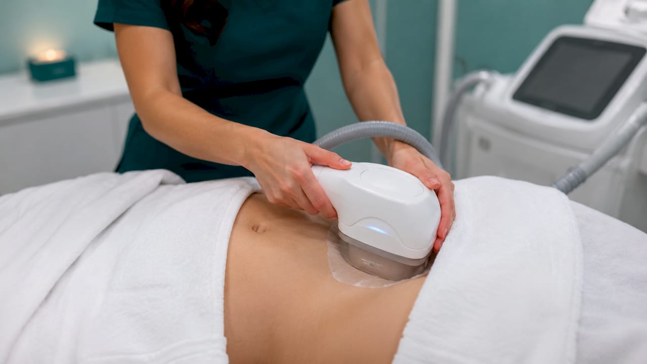Technician applying cryolipolysis device on abdomen