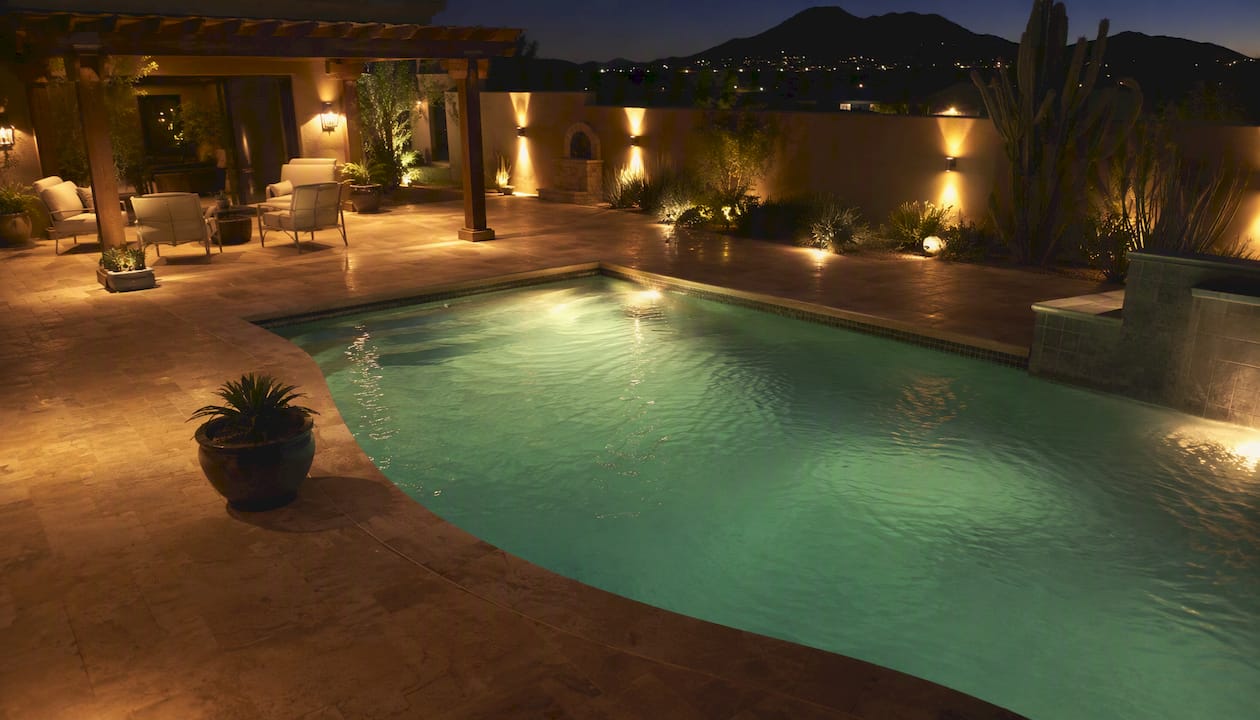 Backyard pool area with warm outdoor lighting