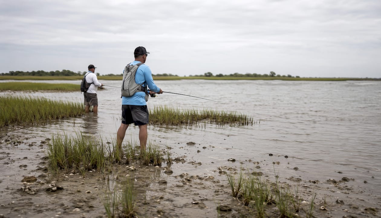 Fishermen casting rods in tidal estuary at mid-tide