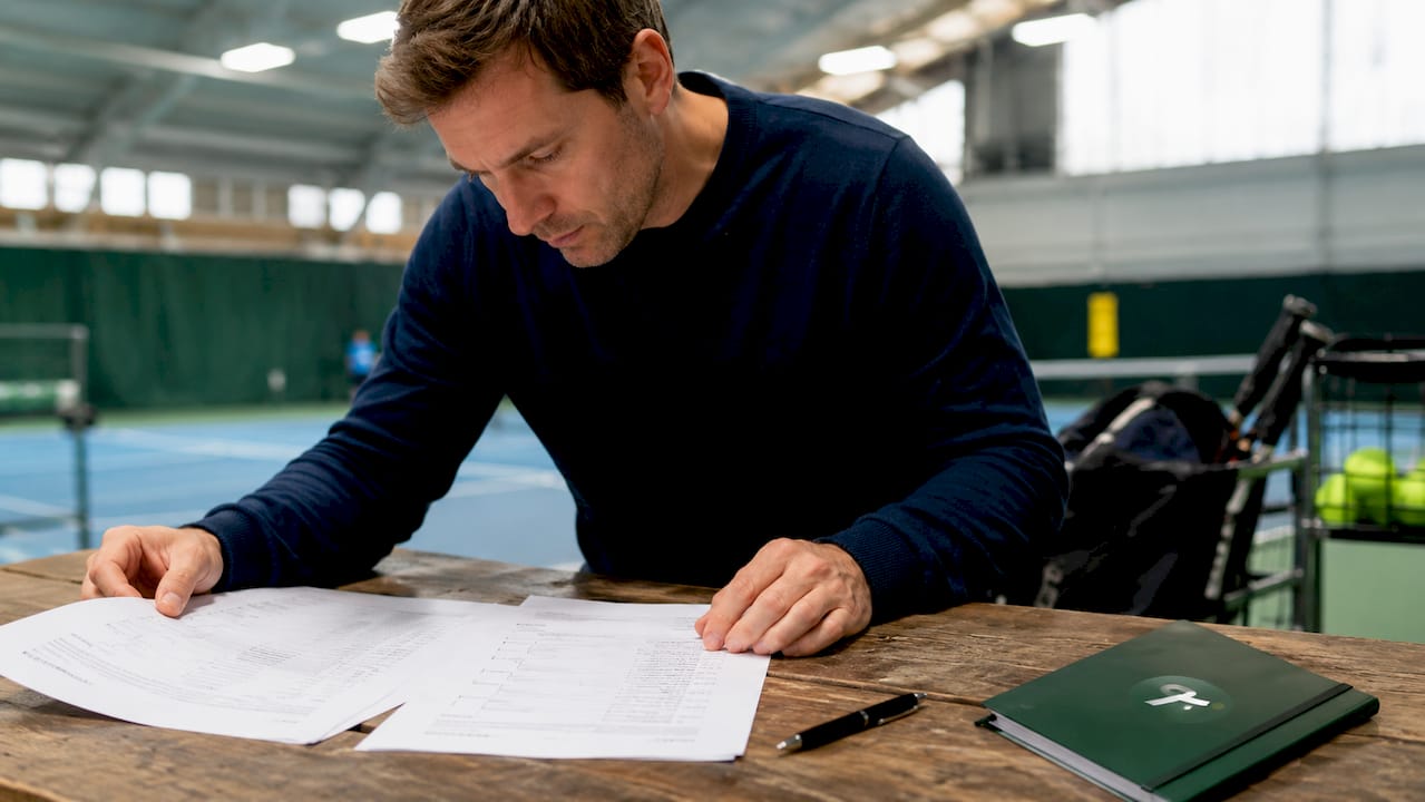 Hands arranging tennis Grand Slam draw sheets