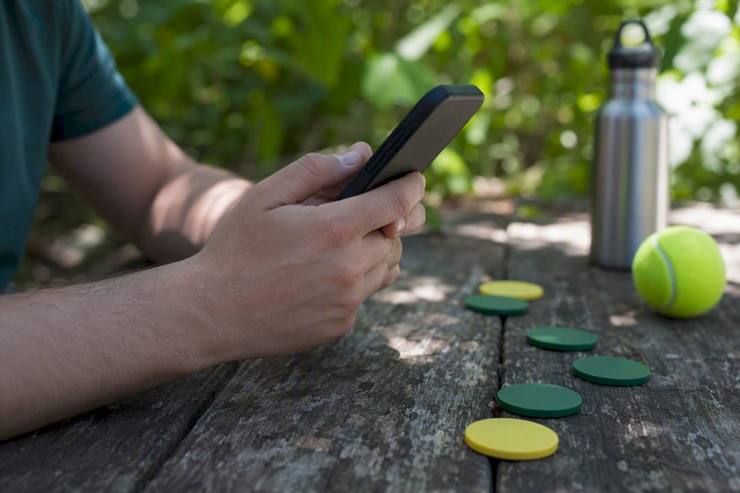 Person playing fantasy tennis on phone outdoors