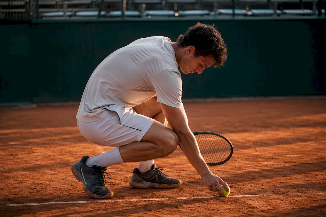Player picking tennis ball during match