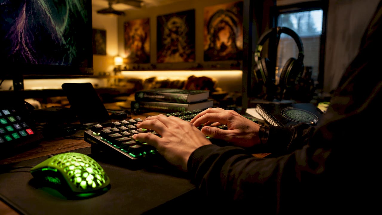 Developer hands typing with gaming mouse and blockchain books