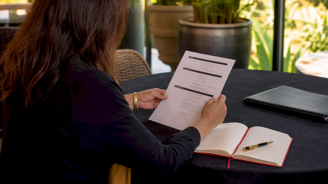 Hands holding executive retreat agenda at meeting table