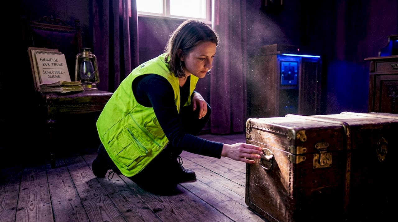 Eine Frau nimmt in einem Escape Room mit spannendem Motto eine Spur ganz genau unter die Lupe.