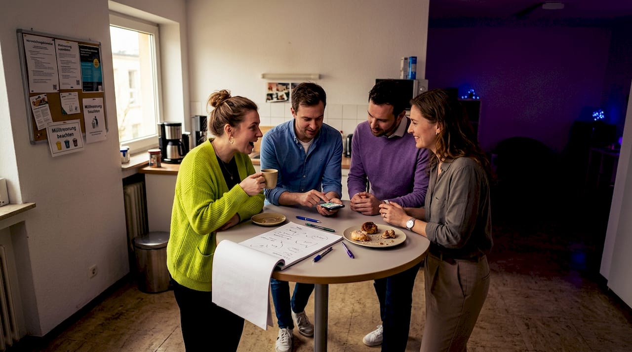 Kolleginnen und Kollegen sitzen gemeinsam am Tisch und tauschen sich darüber aus, wie erfolgreich die Veranstaltung verlaufen ist.