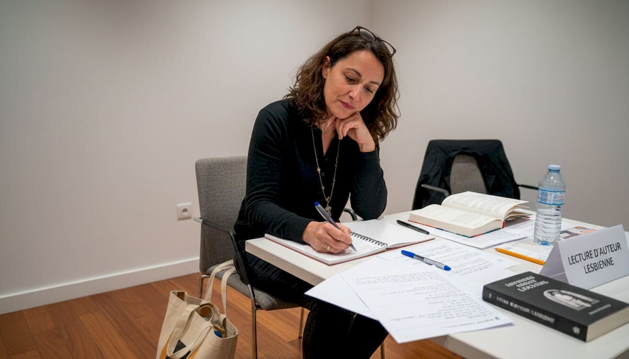 Une femme prend des notes lors d’une rencontre littéraire dédiée à la communauté lesbienne.