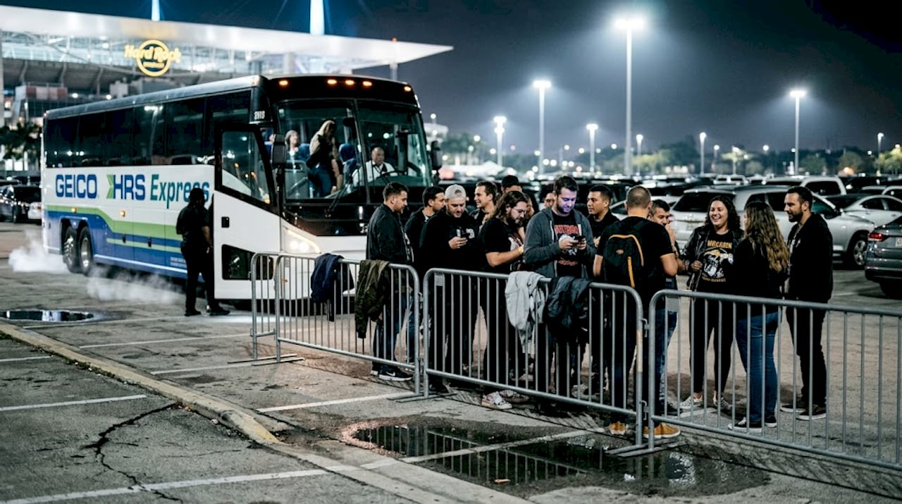 People waiting at stadium shuttle stop lot