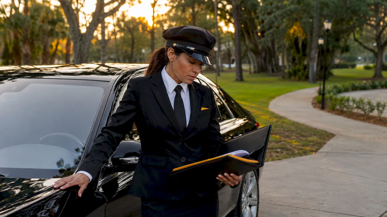 Chauffeur unlocking luxury executive sedan outside office