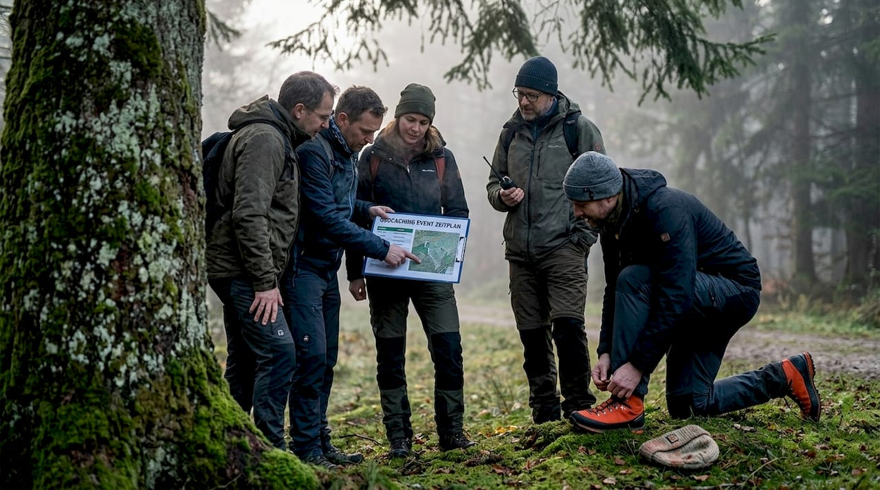 Kleine Geocaching-Gruppe bespricht ihren Ablaufplan für die Schatzsuche im Wald.