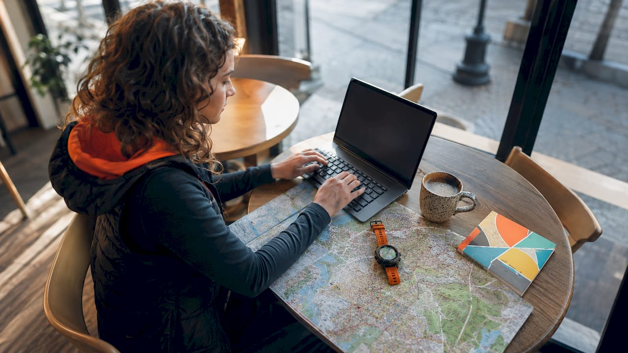 Eine Frau plant ihre Reise mithilfe von Laptop und digitalen Karten.