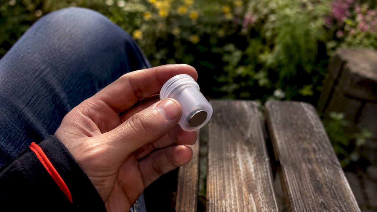 Detailaufnahme: Ein magnetischer PETling-Geocache liegt in der Hand.