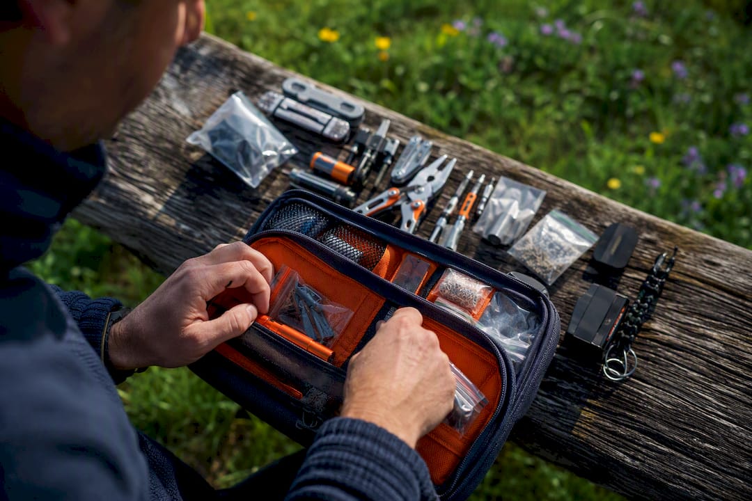 Hände, die zusätzliches Geocaching-Werkzeug einpacken