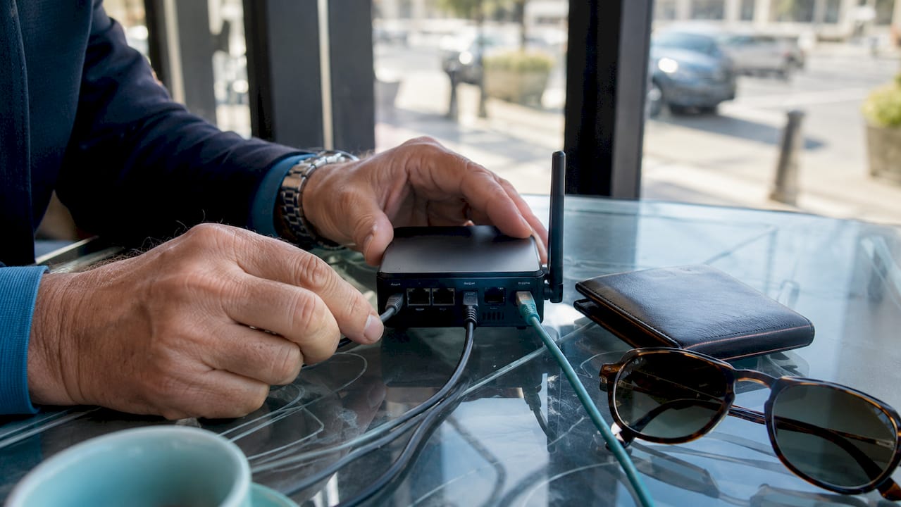 Hands configuring travel router on hotel desk