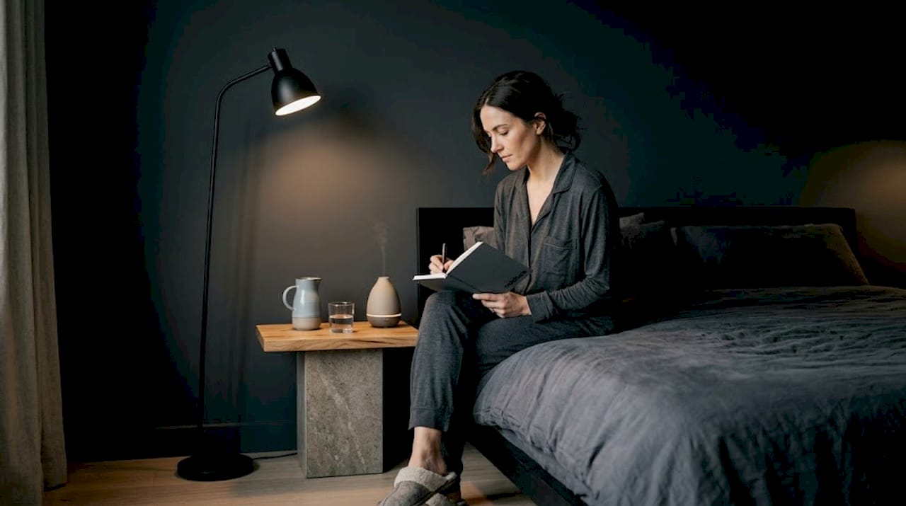 Woman journaling sleep habits in bedroom