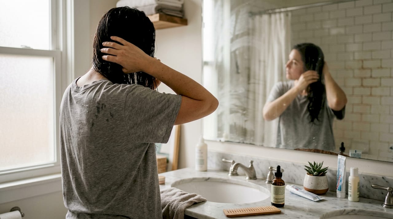Eine Frau trägt während ihrer morgendlichen Haarpflege Spülung auf.