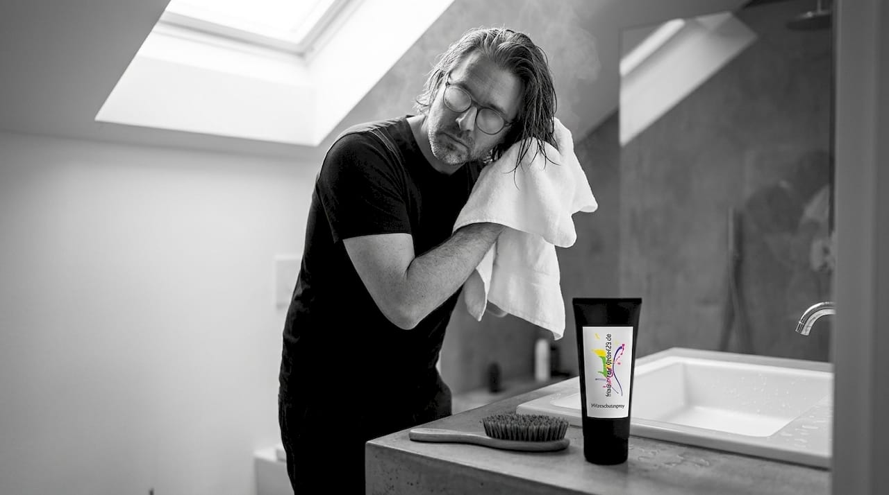 Ein Mann trocknet sein Haar behutsam mit einem Handtuch ab.