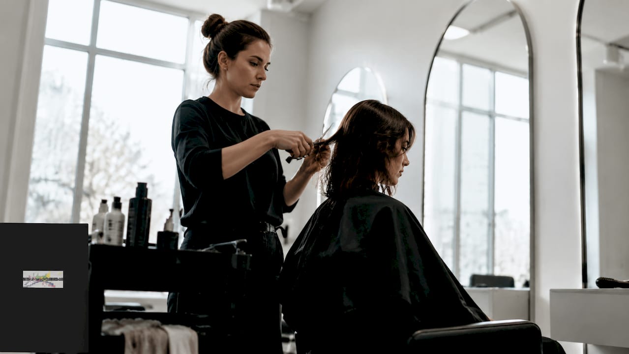Eine Friseurin verpasst einer jungen Frau einen frischen Stufenschnitt.