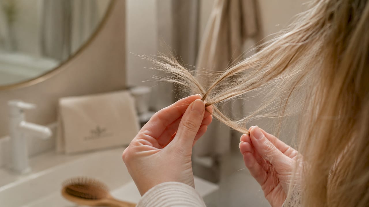 Detailaufnahme von brüchigen Haarspitzen, die in den Händen gehalten werden.